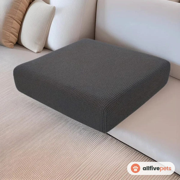 A dark grey stretch slipcover fitted over a sofa seat cushion