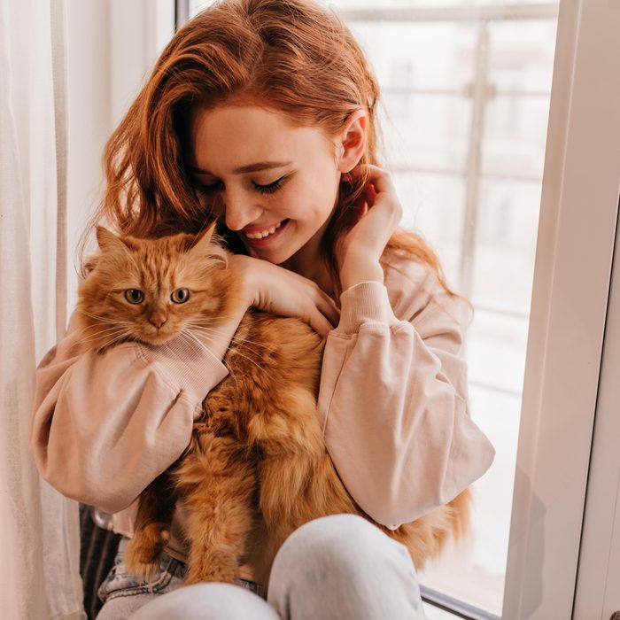 A customer holding her fluffy ginger cat by the window