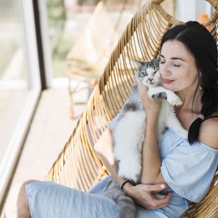 A customer cuddling her grey cat in a hanging chair
