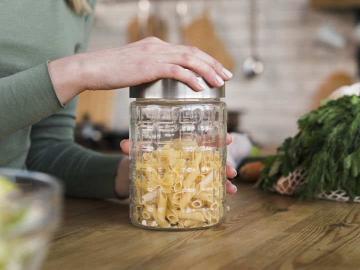 A hand pressing the lid down on a glass storage jar